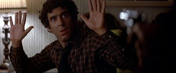 Movie still from “Capricorn One” (1977), directed by Peter Hyams – A man in a plaid dress shirt and tie waving; Close Up shot, Over the shoulder angle