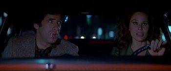 Movie still from “Capricorn One” (1977), directed by Peter Hyams – A man and a woman sitting in the back seat of a car; Close Up shot, Over the shoulder angle