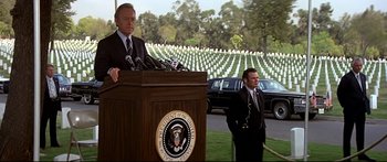 Movie still from “Capricorn One” (1977), directed by Peter Hyams – Two men in suits stand in front of a podium; Wide shot, Over the shoulder angle