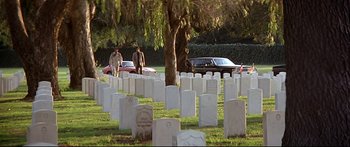 Movie still from “Capricorn One” (1977), directed by Peter Hyams – Two men standing in front of a cemetery with white tombstones in the background; Extreme Wide shot, High angle