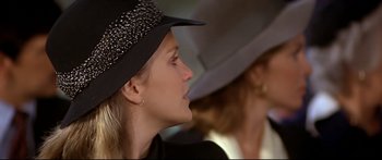 Movie still from “Capricorn One” (1977), directed by Peter Hyams – A woman wearing a black hat looking to the side; Close Up shot, Over the shoulder angle