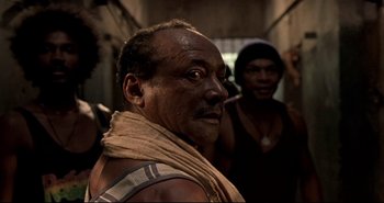 Movie still from “Carandiru” (2003), directed by Hector Babenco – An older man with a scarf around his neck; Close Up shot, Low angle