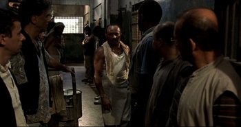 Movie still from “Carandiru” (2003), directed by Hector Babenco – A group of men standing around in a room; Medium shot, Low angle