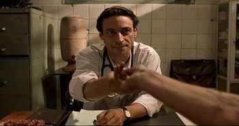 Movie still from “Carandiru” (2003), directed by Hector Babenco – A man shaking hands with another man in a kitchen; Close Up shot, Over the shoulder angle
