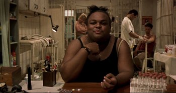 Movie still from “Carandiru” (2003), directed by Hector Babenco – A person sitting at a table with a cell phone in front of him; Close Up shot, Over the shoulder angle