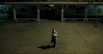 Movie still from “Carandiru” (2003), directed by Hector Babenco – A man standing in an empty parking lot at night; Extreme Wide shot, High angle