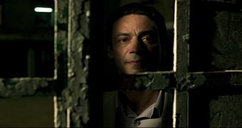 Movie still from “Carandiru” (2003), directed by Hector Babenco – A man standing in a jail cell looking at the camera; Close Up shot, Low angle