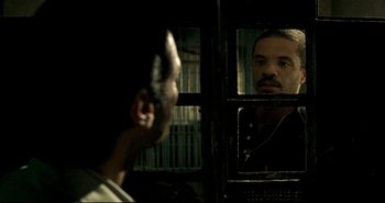 Movie still from “Carandiru” (2003), directed by Hector Babenco – A man looking into a mirror while standing next to another man; Close Up shot, Over the shoulder angle