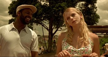 Movie still from “Carandiru” (2003), directed by Hector Babenco – A man and a woman standing next to each other in front of a tree; Medium shot, Over the shoulder angle