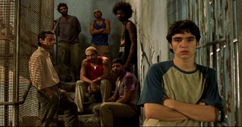 Movie still from “Carandiru” (2003), directed by Hector Babenco – A group of men standing next to each other in front of a wall; Medium shot, Low angle