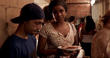 Movie still from “Carandiru” (2003), directed by Hector Babenco – A man and a woman holding a plate of food; Medium shot, Over the shoulder angle