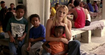 Movie still from “Carandiru” (2003), directed by Hector Babenco – A woman sitting on a chair with two children; Medium shot, Low angle