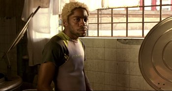 Movie still from “Carandiru” (2003), directed by Hector Babenco – A man with a blonde afro is standing in a bathroom; Close Up shot, Low angle