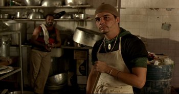 Movie still from “Carandiru” (2003), directed by Hector Babenco – A man wearing an apron in a restaurant kitchen; Medium shot, Low angle