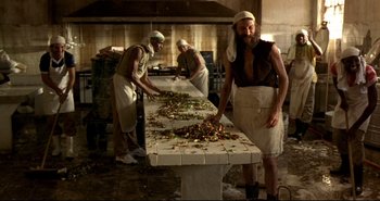 Movie still from “Carandiru” (2003), directed by Hector Babenco – A group of men standing around a table in a kitchen; Medium shot, Low angle
