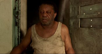 Movie still from “Carandiru” (2003), directed by Hector Babenco – An older man wearing a white tank top and gold necklace; Close Up shot, High angle