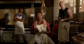 Movie still from “Carandiru” (2003), directed by Hector Babenco – A group of men standing around in a kitchen preparing food; Wide shot, Low angle