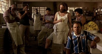 Movie still from “Carandiru” (2003), directed by Hector Babenco – A group of people standing around in a kitchen; Medium shot, Low angle