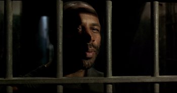 Movie still from “Carandiru” (2003), directed by Hector Babenco – A person behind a metal fence; Close Up shot, Low angle