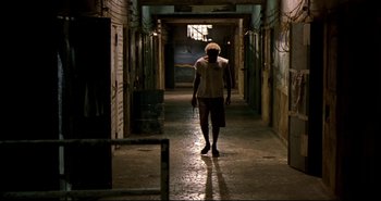 Movie still from “Carandiru” (2003), directed by Hector Babenco – A man walking down a hallway in an alley way; Wide shot, Low angle