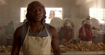 Movie still from “Carandiru” (2003), directed by Hector Babenco – A man wearing an apron standing next to potatoes; Close Up shot, Low angle