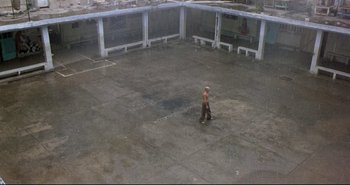 Movie still from “Carandiru” (2003), directed by Hector Babenco – A man is walking in an empty parking lot; Extreme Wide shot, High angle