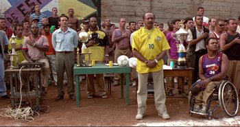 Movie still from “Carandiru” (2003), directed by Hector Babenco – A group of men standing in front of a table with trophies; Medium shot, Low angle