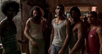 Movie still from “Carandiru” (2003), directed by Hector Babenco – A group of men standing next to each other in a room; Medium shot, Low angle
