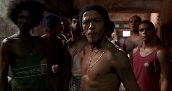 Movie still from “Carandiru” (2003), directed by Hector Babenco – A group of men standing around a building; Medium shot, Low angle