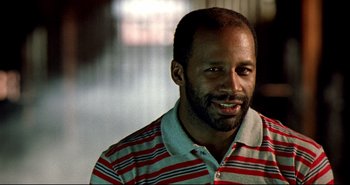 Movie still from “Carandiru” (2003), directed by Hector Babenco – A person wearing a striped shirt smiling; Close Up shot, Low angle