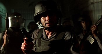 Movie still from “Carandiru” (2003), directed by Hector Babenco – A man wearing a helmet and holding a gun; Close Up shot, Low angle