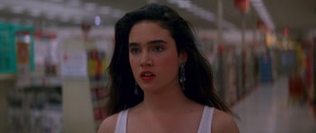 A woman with long black hair wearing a white tank top