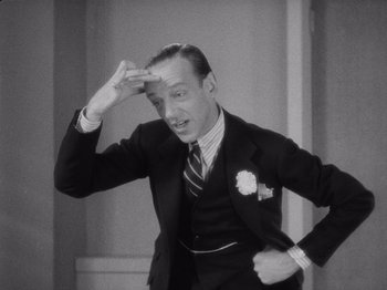 Movie still from “Carefree” (1938), directed by Mark Sandrich – A man in a suit and tie holding his hand up to his forehead; Close Up shot, Low angle