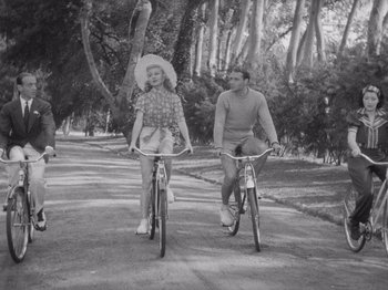 Movie still from “Carefree” (1938), directed by Mark Sandrich – A man and a woman riding bikes down a street; Wide shot, High angle