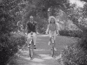 Movie still from “Carefree” (1938), directed by Mark Sandrich – A man and a woman riding bikes down a path; Wide shot, High angle