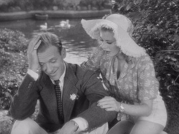 Movie still from “Carefree” (1938), directed by Mark Sandrich – A man and a woman sitting next to a body of water; Medium shot, High angle