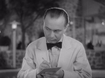 Movie still from “Carefree” (1938), directed by Mark Sandrich – A black and white photo of a man writing on a piece of paper; Close Up shot, High angle