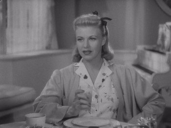 Movie still from “Carefree” (1938), directed by Mark Sandrich – A black and white photo of a woman sitting at a table; Close Up shot, High angle