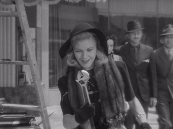Movie still from “Carefree” (1938), directed by Mark Sandrich – An old black and white photo of a woman holding a book; Medium shot, Low angle