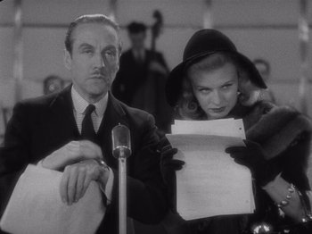 Movie still from “Carefree” (1938), directed by Mark Sandrich – A man and a woman are holding papers and a microphone; Medium shot, Over the shoulder angle
