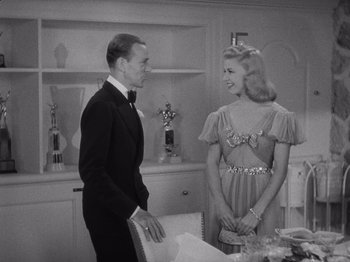 Movie still from “Carefree” (1938), directed by Mark Sandrich – A man and a woman standing next to each other in a room; Medium shot, High angle