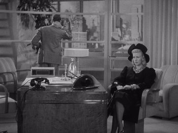 Movie still from “Carefree” (1938), directed by Mark Sandrich – An old photo of a woman sitting at a desk; Medium shot, High angle