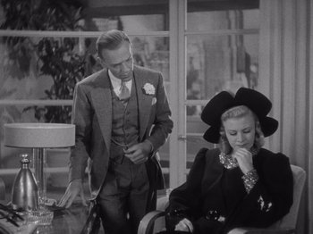 Movie still from “Carefree” (1938), directed by Mark Sandrich – A man and a woman looking at their cell phones; Medium shot, Over the shoulder angle