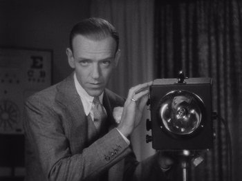 Movie still from “Carefree” (1938), directed by Mark Sandrich – A man in a suit and tie holding a camera; Close Up shot, Low angle