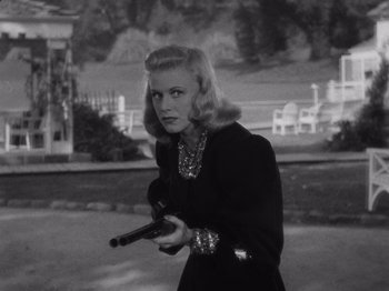 Movie still from “Carefree” (1938), directed by Mark Sandrich – A black and white photo of a woman holding a gun; Medium shot, Low angle