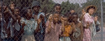 Movie still from “Carmen Jones” (1954), directed by Otto Preminger – A group of children standing behind a fence; Medium shot, High angle