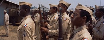 Movie still from “Carmen Jones” (1954), directed by Otto Preminger – A group of men in tan uniforms holding guns; Medium shot, High angle