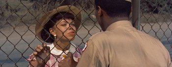 Movie still from “Carmen Jones” (1954), directed by Otto Preminger – An african - american woman talking to an african - american man behind a chain link fence; Close Up shot, Over the shoulder angle