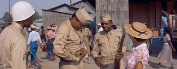 Movie still from “Carmen Jones” (1954), directed by Otto Preminger – Two men in tan uniforms are standing next to each other holding guns; Medium shot, Low angle