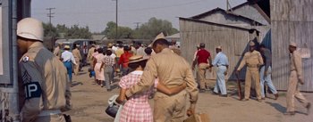 Movie still from “Carmen Jones” (1954), directed by Otto Preminger – An african - american couple walking in a crowd of people; Medium shot, High angle